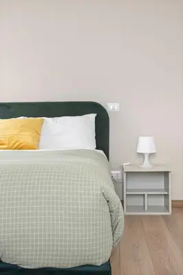 a bed with a green and white comforter and a side table at Sunny House Gianicolo in Rome