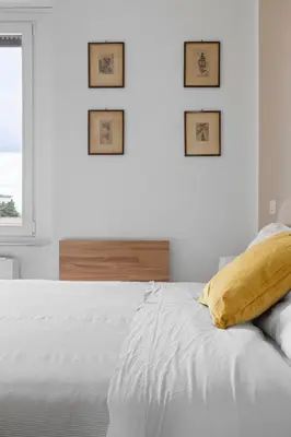 a white bedroom with a bed with three pictures on the wall at Sunny House Gianicolo in Rome