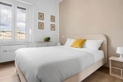 a white bedroom with a large bed and a window at Sunny House Gianicolo in Rome