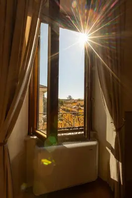a window in a room with the sun shining through at RosaM Suite - Via Veneto 15 min walk from Spanish Steps Top Floor Luxury Apartment in Rome
