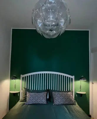 a bedroom with a green wall and a large chandelier at Villa Borghese Green Apartment in Rome