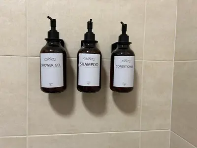three bottles of shampoo on a tiled wall at Miro Home II in Rome