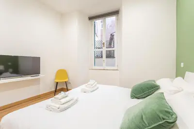 a white bedroom with a bed and a yellow chair at 2 BDR Navona Quintessential Charm in Rome