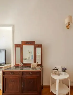 a wooden dresser with a mirror and a white stool at SAN PIETRO VATICAN AREA LARGE APARTMENT - near SUBWAY in Rome