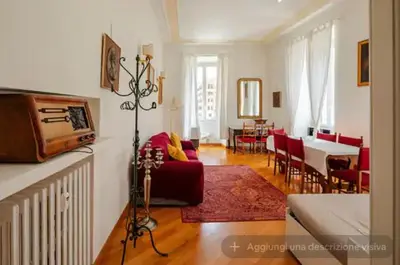 a living room with a red couch and a dining room at SAN PIETRO VATICAN AREA LARGE APARTMENT - near SUBWAY in Rome