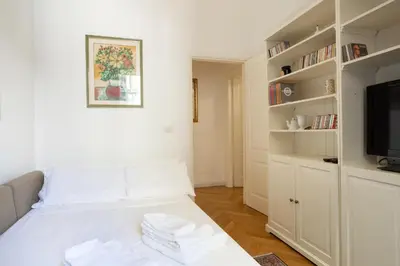a small bedroom with a white bed and a tv at Domus Alba Mantua in Rome