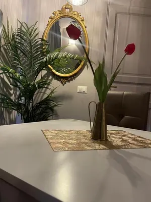 a vase with flowers on a table with a mirror at Lucilla’s Suite San Pietro station in Rome