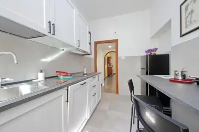 a kitchen with white cabinets and a black refrigerator at 4BNB - Leone IV Apartment in Rome
