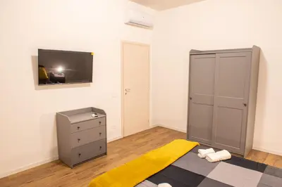 a room with a tv and a dresser with a yellow rug at Locazioni Ostiense - Domus William in Rome
