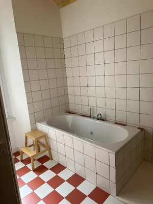 a bath tub in a tiled bathroom with a stool at Santamaura Vatican Apartment in Rome