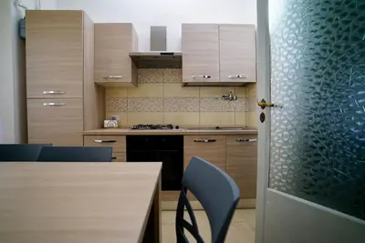 a kitchen with a table and blue chairs and a door at (9)Nine stops from the Colosseum in Rome