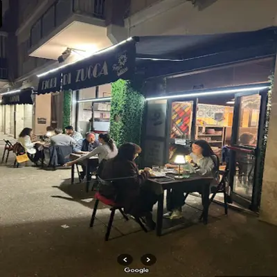 people sitting at tables outside a restaurant at night at Rome Apartment Marconi in Rome