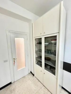 a kitchen with white cabinets and a door at Cuore di Marconi Apartment in Rome