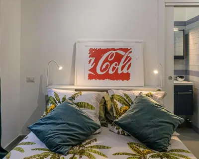 a coca cola sign above a bed with pillows at Belle Arti home in Rome