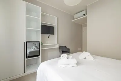 a white bedroom with a bed and a tv at Belli Suites Vatican Rome Guest House in Rome