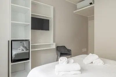 a bedroom with a bed and a tv and a chair at Belli Suites Vatican Rome Guest House in Rome