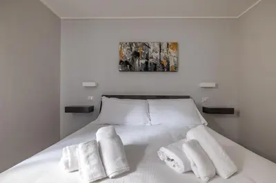 a bedroom with a white bed with towels on it at Belli Suites Vatican Rome Guest House in Rome