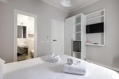 a white bedroom with two towels on a bed at Belli Suites Vatican Rome Guest House in Rome