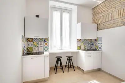 a kitchen with white cabinets and two stools at Joyful 148 Luxury Guest House in Rome