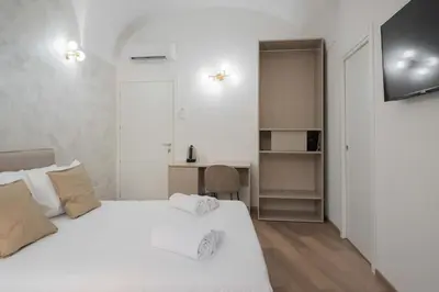a bedroom with a white bed and a desk at ELICAL Vatican Suites in Rome
