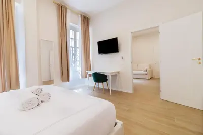 a white hotel room with a bed and a desk at Charme & Chic Nazionale in Rome