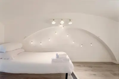 a white bedroom with a white bed with lights at Sanniti Loft San Lorenzo in Rome