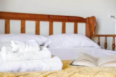 a stack of towels on a bed with a book at ArtStay AC Apt Near Metro, Fiumicino Airport in Rome