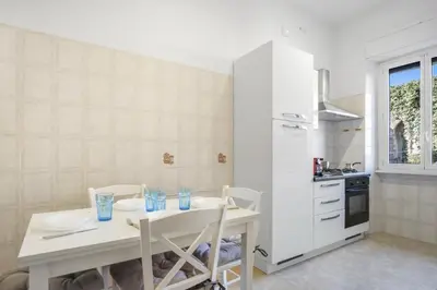 a white kitchen with a white table and chairs at ArtStay AC Apt Near Metro, Fiumicino Airport in Rome