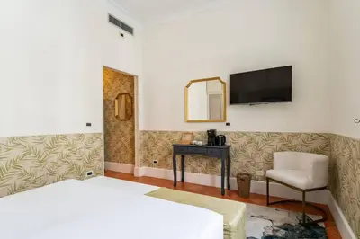 a bedroom with a bed and a chair and a television at Fori Imperiali Luxe Mansion in Rome