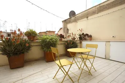 a table and chairs on a balcony with potted plants at Statonia Terrace Penthouse in Rome