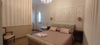 a bedroom with a bed and a chair and a chandelier at Maison Bonheur in Rome