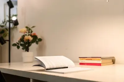 an open book on a desk with a vase of flowers at Central near Piazza Navona by NDP rent in Rome