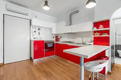 a red kitchen with white cabinets and a white table at Portuense 107 - Bright Flat in Rome