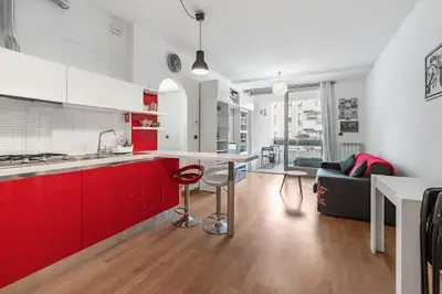 a kitchen with red cabinets and a table and a couch at Portuense 107 - Bright Flat in Rome