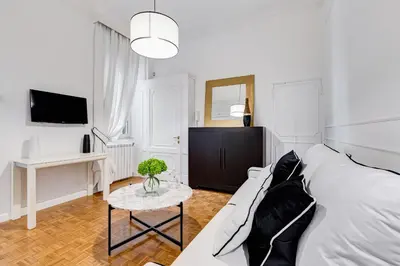 a white bedroom with a white couch and a table at New Sistina Suite - Your Italian Holidays in Rome