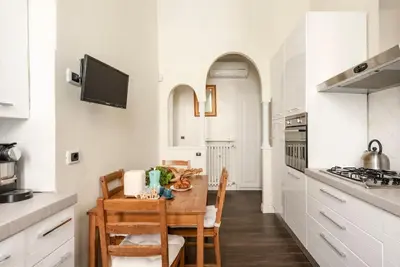 a white kitchen with a wooden table and chairs at Luxury Blu Rome in Rome