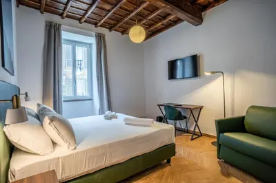 a bedroom with a bed and a green chair at Fantini Rooms-Monti in Rome
