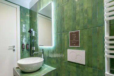 a green tiled bathroom with a sink and a mirror at Fantini Rooms-Monti in Rome