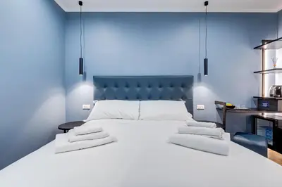 a bedroom with a large white bed with a blue headboard at LISA SUITE in Rome