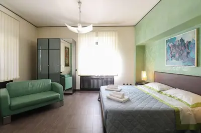 a bedroom with a large bed and a green chair at Parioli Suites Apartments in Rome