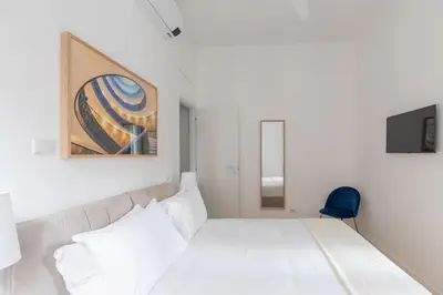 a bedroom with a white bed and a blue chair at iFlat Vatican 2 Bedroom Design Apartment in Rome