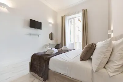 a white bedroom with a large bed and a window at Labi Home Colossevm in Rome