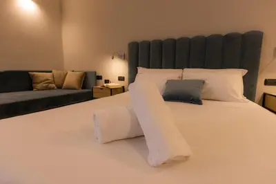 a bedroom with a large white bed with a couch at Villa Borghese Prestige Rooms in Rome