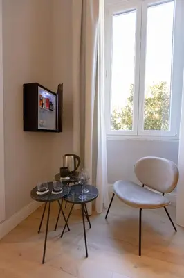 a living room with a table and a chair and a tv at Villa Borghese Prestige Rooms in Rome
