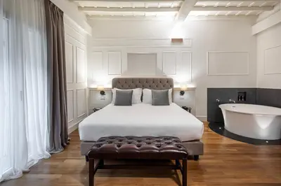 a bedroom with a large bed and a bath tub at Palazzo Goldoni Condotti Collection in Rome