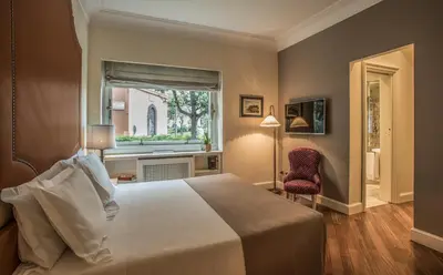 a bedroom with a bed and a window and a chair at 47Luxury Suites - Colosseo in Rome