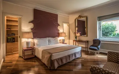 a bedroom with a bed and a chair and a window at 47Luxury Suites - Colosseo in Rome