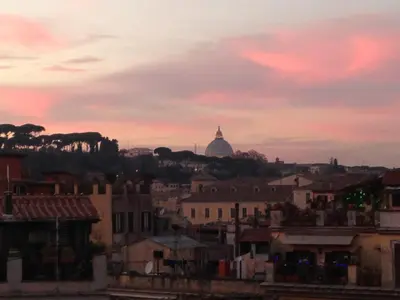 a view of a city at sunset with a dome at Stylish Penthouse with terrace in Trastevere in Rome