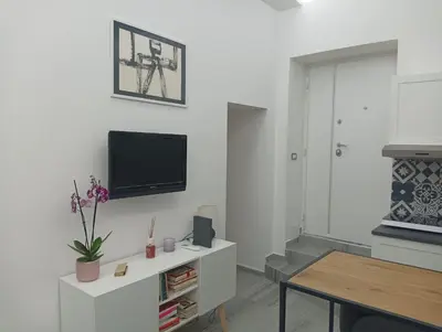 a white living room with a tv on a wall at Domus Fanti in Rome