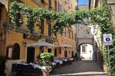 an alley with tables and umbrellas in a city at MyRentalInn - Rome - Trastevere Arch Suite in Rome